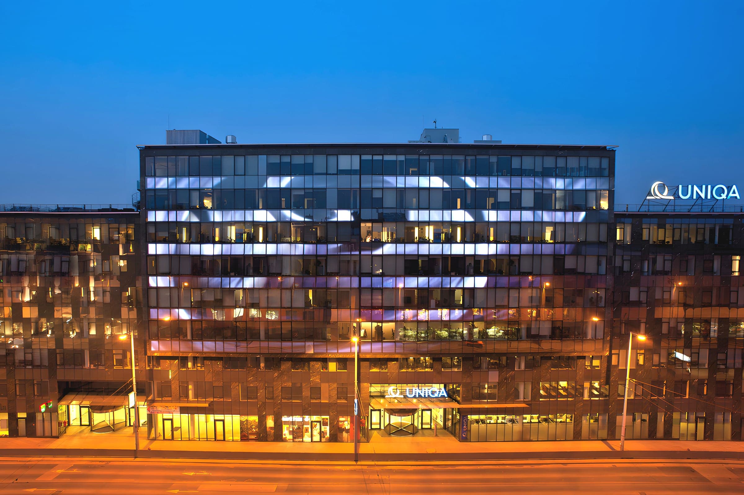 The lit facade of Vital Business Center at night, seen from Róbert Károly körút